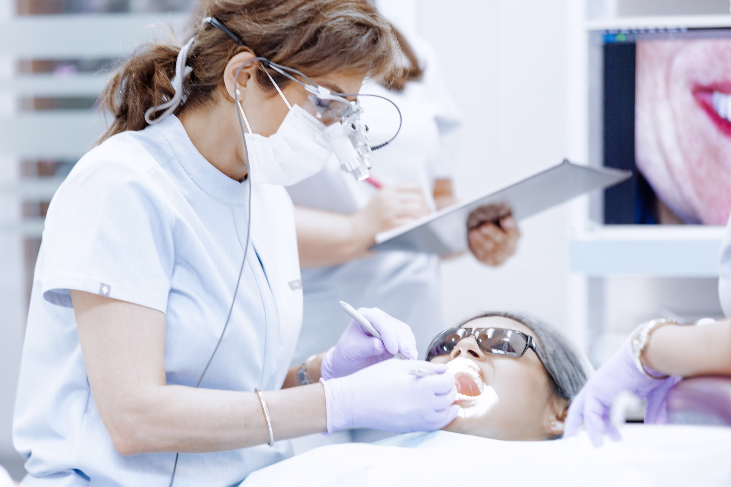 A cosmetic dentist wearing dental loupes and gloves performs an oral examination on a patient at Georgetown Cosmetic Dentistry in Washington DC.