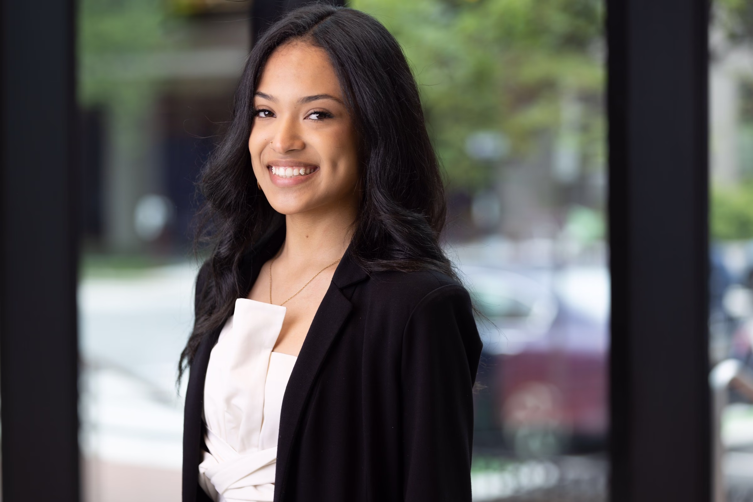 A young woman with a radiant, confident smile wearing professional attire outside Georgetown Cosmetic Dentistry in Washington DC.